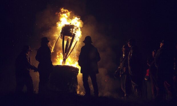 People silhouetted against the burning Clavie in Burghead.
