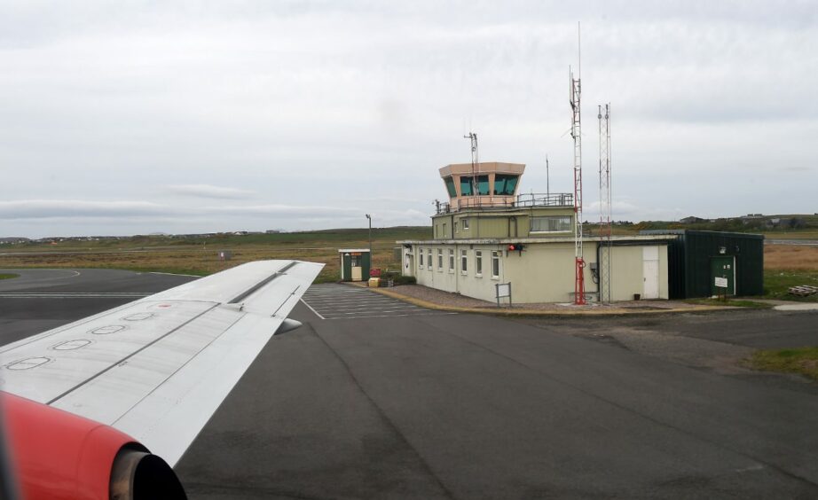 Air Traffic Control tower with wing of taxiing aircraft in front of it.