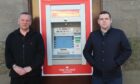 Forres postmaster Paul McBain and Moray MP Douglas Ross standing either side of the Post Office ATM.
