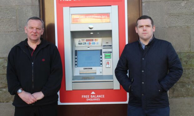 Forres postmaster Paul McBain and Moray MP Douglas Ross standing either side of the Post Office ATM.