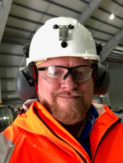 Close up shot of Scotgold CEO wearing a reflective orange jacket, white helmet and noise-cancelling earmuffs