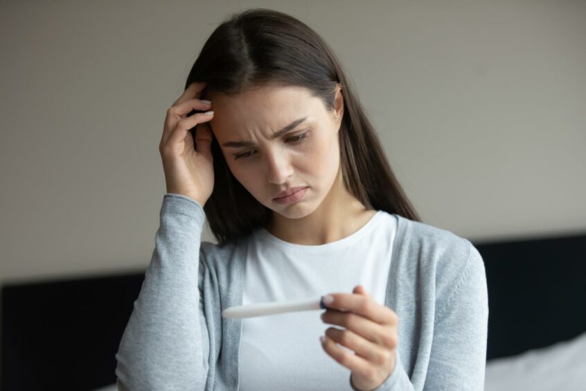 Disappointed looking woman holding negative pregnancy test in her hand
