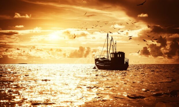 Fishing boat at sea as sun sets.