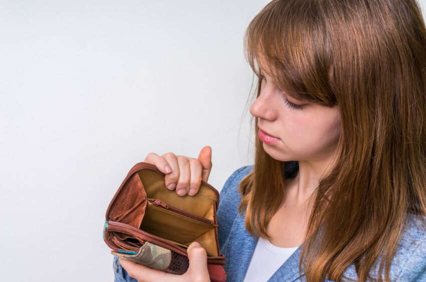 Concerned woman looking inside purse with no money inside