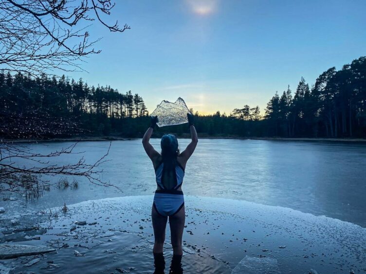 Trini Graham-Stewart holding a piece of ice aloft from the frozen loch. 