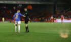 Rangers' James Tavernier gestures towards a flare with referee Kevin Clancy during the game at Pittodrie