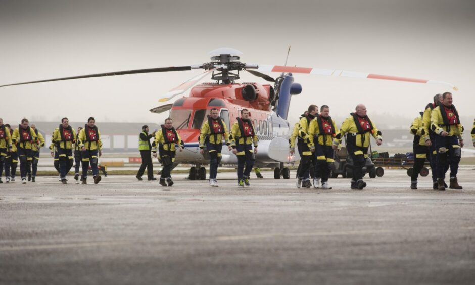 Offshore workers with a CHC Scotia helicopter at Aberdeen heliport. 