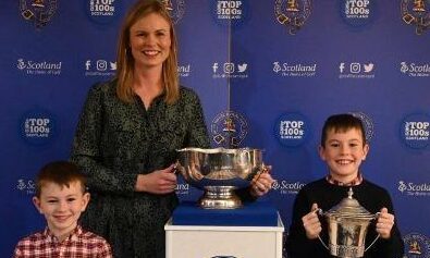 Ashley Lovie gets the help of her two boys Aiden, left, and Taylor, right, to show off her winning trophies.