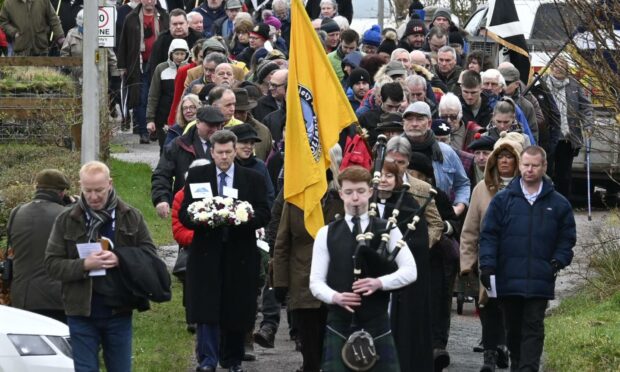Attendees walked to the memorial cross while piper Calum Macaskill played. Photo: Iain Ferguson.