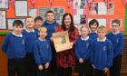 Mrs Sutherland with P5/6/7 pupils at Bracoden School, and the copy of the Evening Express her father-in-law bought to read about King George VI's death in 1952.