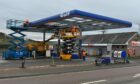 Cranes lift workers to the roof of the Huntly A96 petrol station.