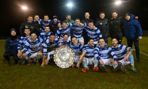 The Banks o' Dee players and management celebrate winning the Aberdeenshire Shield after victory against Huntly