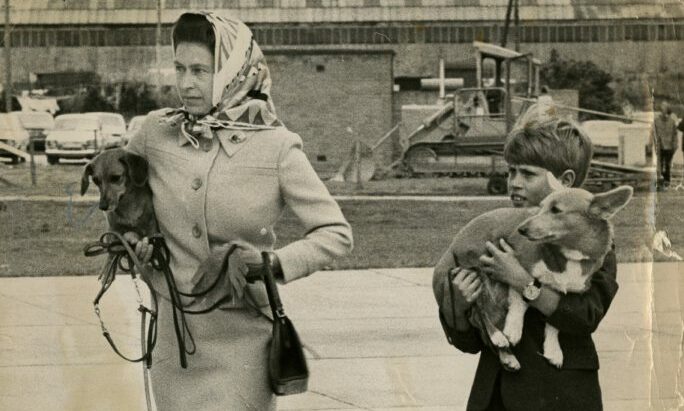 The Queen and Prince Edward walk to their aircraft at Aberdeen Airport carrying two of their dogs in 1974.