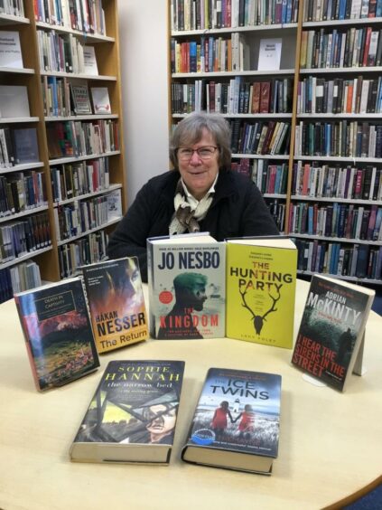 Saturday Slaughters co-ordinator, Marghie West, along with a selection of crime books the reading group has read.