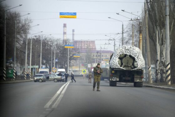 A Ukrainian soldier stands next to a military vehicle on a road in Kramatosrk, eastern Ukraine, Thursday, Feb. 24, 2022.