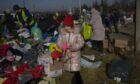 A Ukrainian refugee girl collects a toy from a pile of donated clothes at the Medyka border crossing, in Medyka, Poland. AP Photo/Bernat Armangue