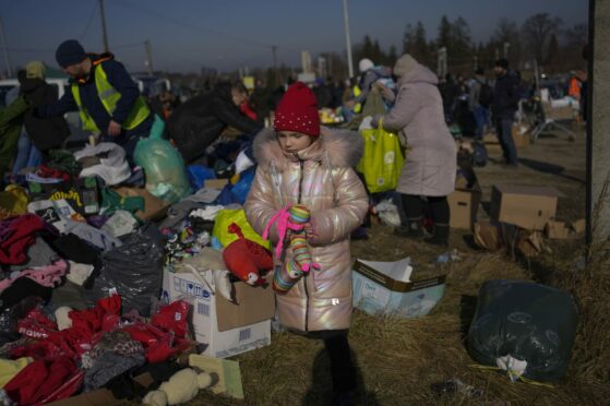 A Ukrainian refugee girl collects a toy from a pile of donated clothes at the Medyka border crossing, in Medyka, Poland. AP Photo/Bernat Armangue