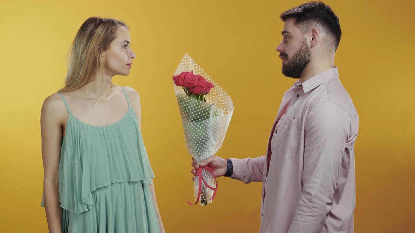Man handing unappreciative woman a bouquet of flowers - how to avoid these relationship mistakes