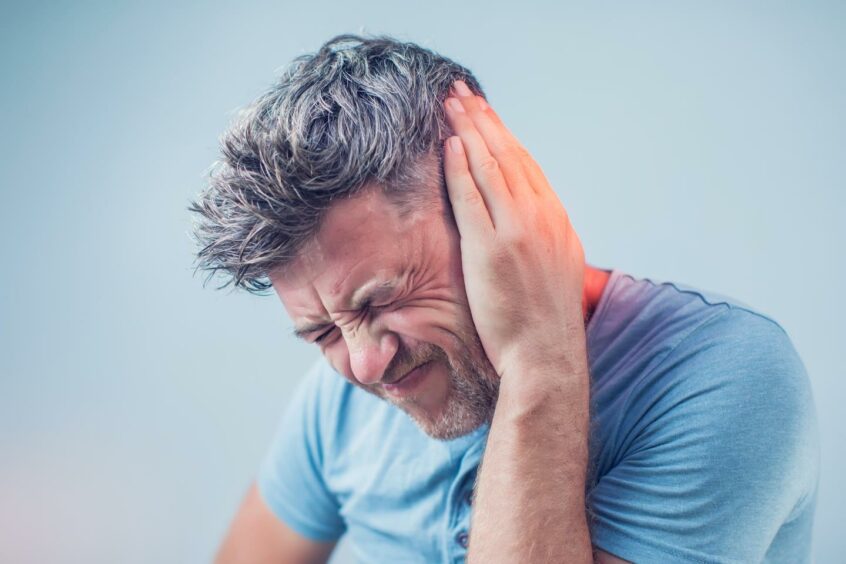 A man covers side of his head due to ringing in the ears.