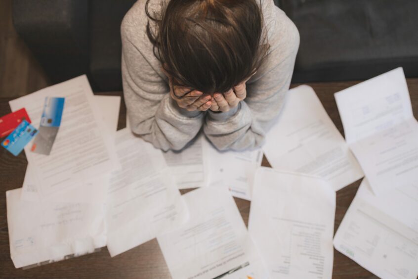 Young lady appearing stressed while surrounded by paperwork.