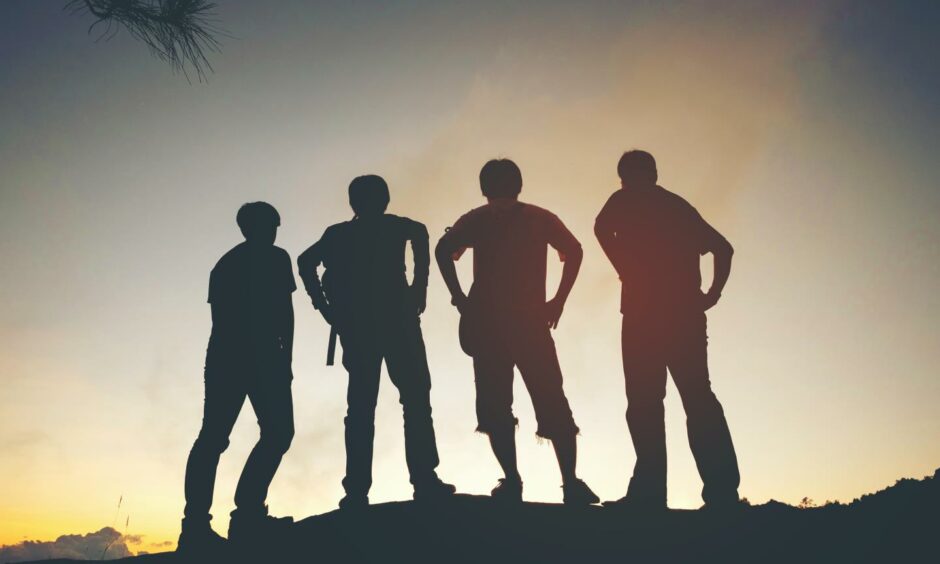Four friends silhouetted by the sun