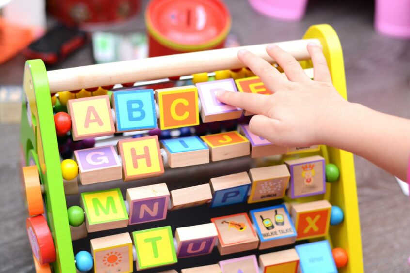 A child playing with colourful blocks with letters painted on them.