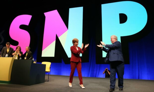 Scotland's first minister Nicola Sturgeon and Westminster SNP leader Ian Blackford applaud each other at their party's 2019 conference (Photo: Andrew MacColl/Shutterstock)