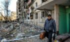 A man seen with a briefcase near apartment building in Kyiv that was shelled by the Russian army. Photo by Sergei Chuzavkov/SOPA Images/Shutterstock