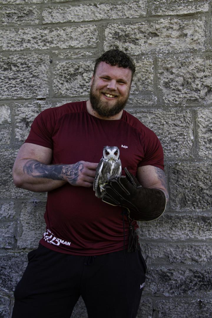 World's Strongest Man Tom Stoltman with Asher, the North African White-Face Scops owl at Blue Highland bird rescue.