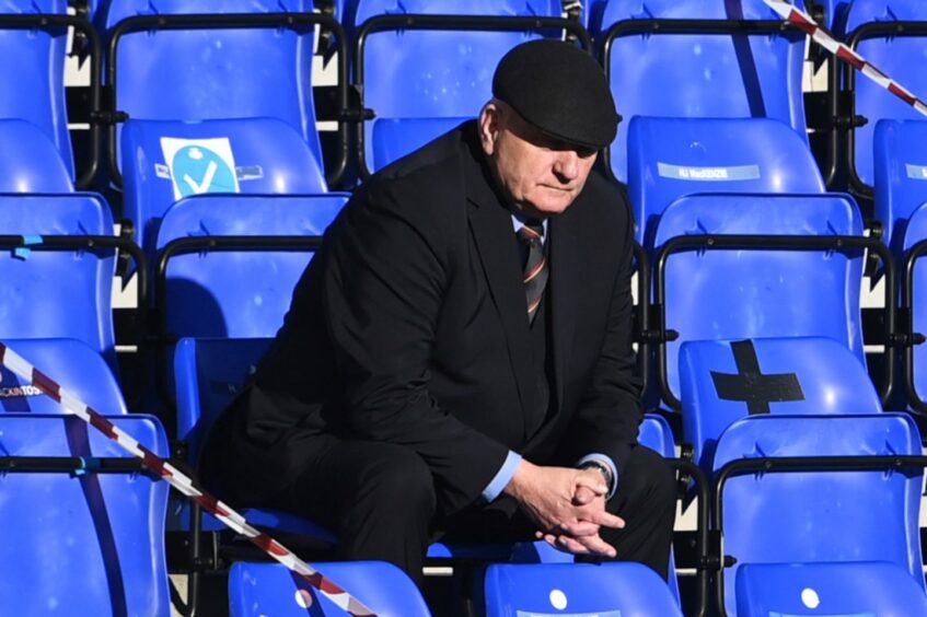 Arbroath manager Dick Campbell sitting on blue bleachers.