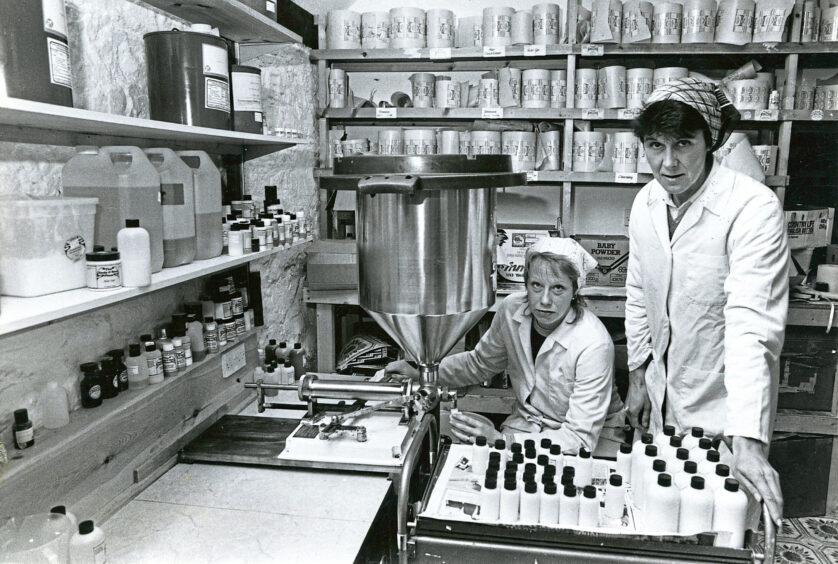 Two factory workers filling up lotion bottles