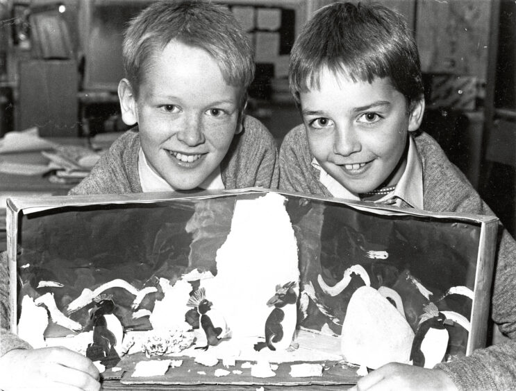 Black and white photo of two school boys showing their project to the camera
