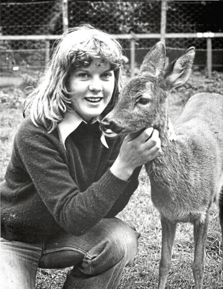 Black and white photo of a woman petting a young deer