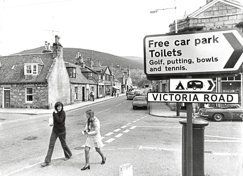 Black and white photo of a road in Ballater with road signs indicating Victoria Road and car park facilities