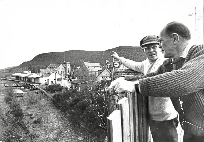 Black and white photo of two men looking over and pointing towards Ballater's former railway station