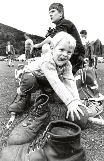 Black and white photo of 3-year-old Andrew Cullen wearing boots and holding a ball