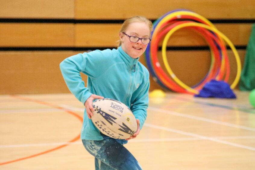 A child smiling while playing rugby at the Orkney Para-sport festival