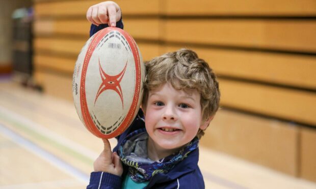 School boy holding a rugby ball.