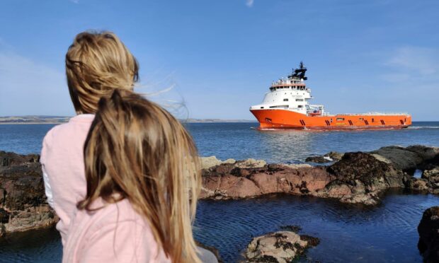 Child sitting with her back to the camera looking at a boat