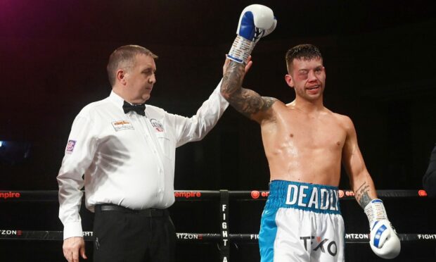 Dean Sutherland's arm is held aloft by referee Kenny Pringle