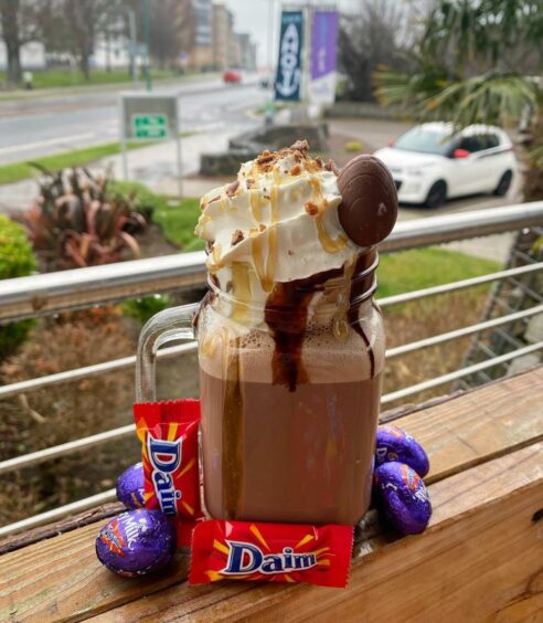 A handled jam jar filled with hot chocolate, whipped cream and topped with a Daim chocolate egg