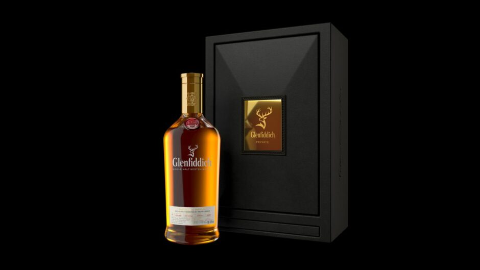 Bottle of Glenfiddich in front of black case carrying the brand's name and logo