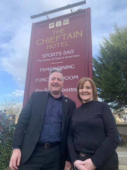 Gary Campbell and Liz Lawson stand in front of The Chieftain Hotel sign