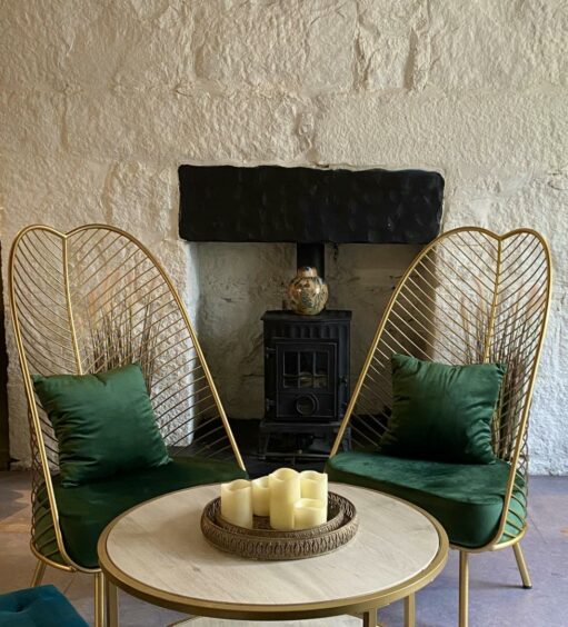 A table in the Barbalow bar with gold chairs with forest green cushions