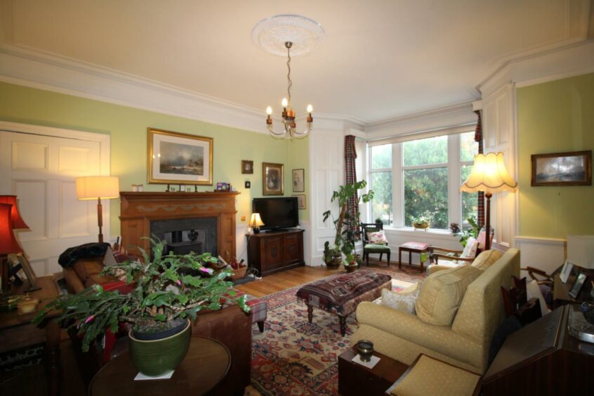 The large lounge with pistachio coloured walls, large windows and a multi-fuel burning stove
