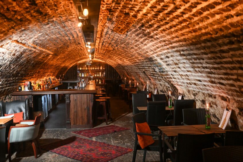 The tunnel-like venue with the bar, tables and chairs