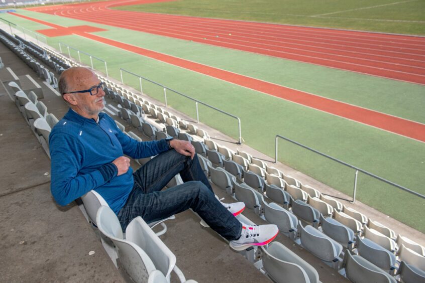 Fraser Clyne in jeans and blue top sitting on the bleachers facing the tracks at Aberdeen Sport village.