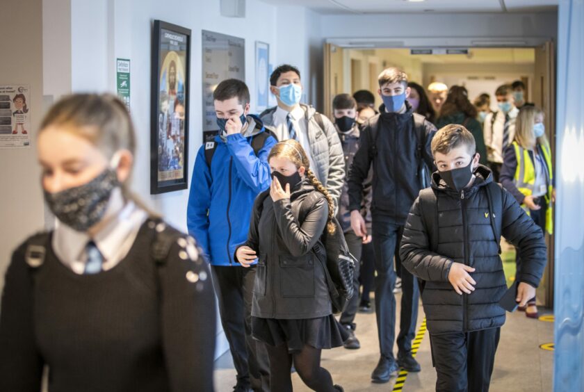 Children of different ages walking in the school hallway.