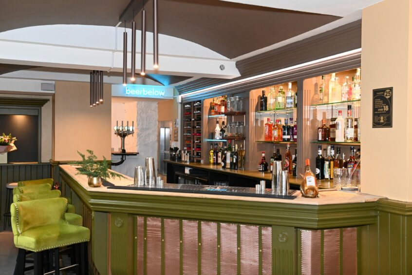 The bar area, with lime green seats and shelves of alcohol in the back