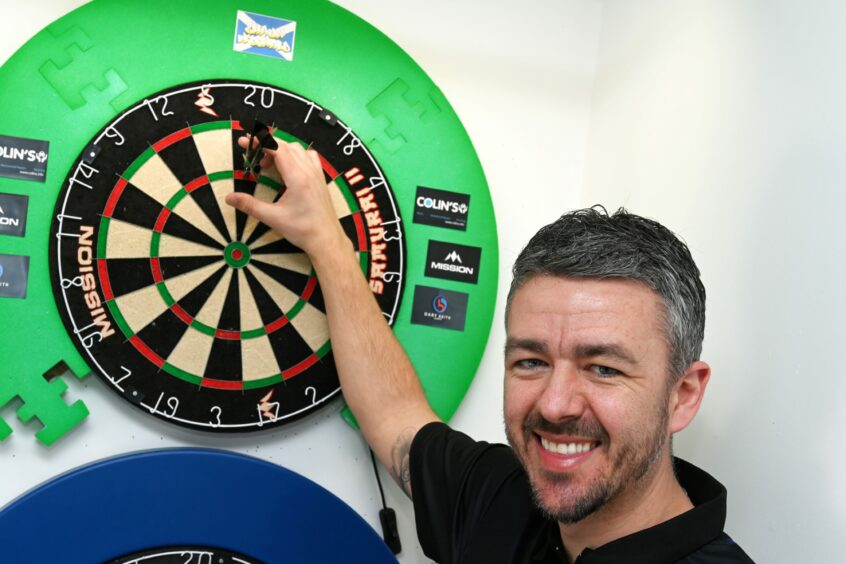 McDonald taking two darts off the dartboard